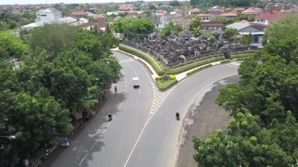 バリ島ドローンで撮影された美しい丸みを帯びた空中ショット。Jalan Bypass高速道路のロータリーでの交通。インドネシアバリのデンパサールにあるPatung Titi Banda記念碑の空中ドローン映像 — ストック動画