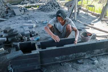 Bir taş ustası Endonezya 'nın Bali adasındaki bir Hindu tapınağına sunak yapıyor. Bir adam taş levhalara katılır ve yapıştırır. El Aletleriyle Taş Kesen Adam