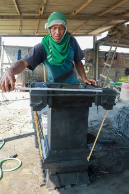 Asyalı adam fabrikadaki taş levhaları ölçer. Endüstriyel fabrika arka planında kesilmiş taş levhalar. Endonezya 'da, Bali' de imalat işçisi.