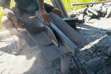 İnsan siyah taşı kesmek için taş kesiciyi kullanır.