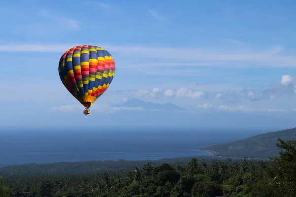 Kleurrijke heteluchtballon vliegen over de blauwe zee. Grote blauwe heteluchtballon die in lichtblauwe lucht met kopieerruimte vliegt — Stockfoto