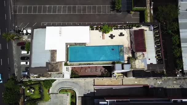 Aerial looking down rising up from rooftop pool. Bali Indonesia Aerial Birdseye to panning view of rooftop pool and street — Stock Video