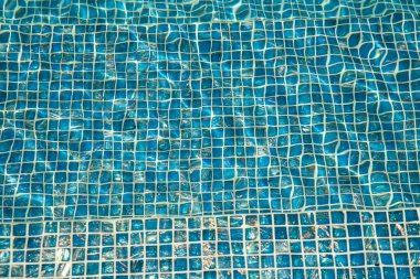 Mavi seramik fayanslı ve su dalgalanması efektli bir havuz. Mavi suyun Ripple ile yüzme havuzunda korunması. Bir turkuaz mozaik fayans yapısının yakın çekimi