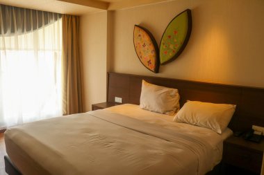 Kuta, Bali, Endonezya, 14 Mart 2021. Mobilyalı modern yatak odası tasarımı. Dekoratif ışık. Komodinli bahar yatağı