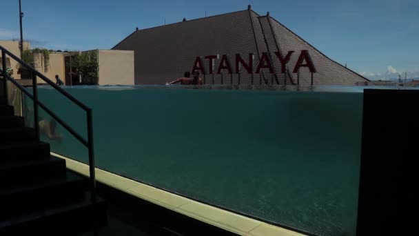 Kuta, Bali, Indonesia, 14 de marzo de 2021. Foto submarina del hombre caucásico buceando en la piscina con pared de cristal transparente en el hotel Atanaya. borde de la piscina infinito de lujo — Vídeo de stock