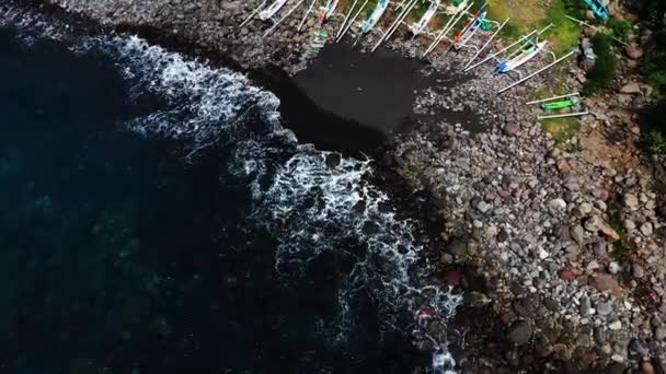 Вгорі з повітря традиційні човни-дзюкунги відпочивають на пляжі на Балі. Біч Амед на Балі Індонезія з рибальськими човнами Юкунг вишикувані на березі, згори вид сковороді вниз. — стокове відео