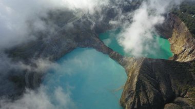 Kelimutu volkanı kraterlerindeki volkanik göllerin üzerindeki bulutlar. Üçünden ikisi Kelimutu Dağı 'ndaki üç renkli volkanik göller, hava manzaralı.