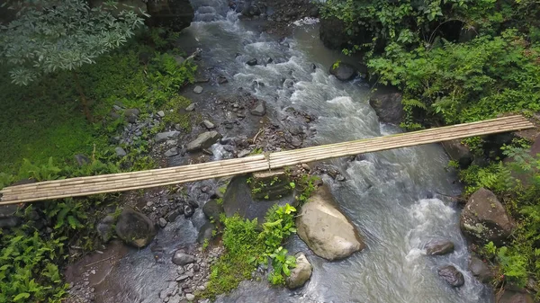 Vista aérea a la pasarela de bambú sobre el río. Puente de bambú sobre un arroyo en un sendero forestal natural — Foto de Stock