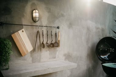 Modern ev mutfağının tasarımı. Çatı katı tarzı ve kırsal. Raflı siyah duvar, tepsiler, kavanozlar, kupalar, lavabo