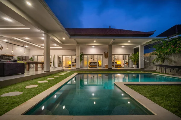 Villa tropical con vista al jardín, piscina y salón abierto al atardecer —  Fotos de Stock