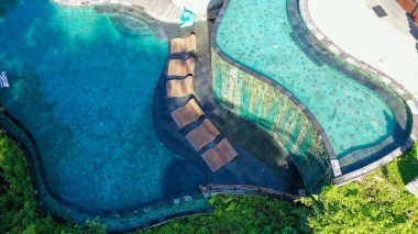Lüks Tatil Köyü 'ndeki Sonsuz Otel Havuzu. Tropikal ormanlarda ve palmiye ağaçlarında beyaz şemsiyeli lüks yuvarlak havuz manzarası. Lüks villa, ormanda yüzme havuzu, Ubud, Bali