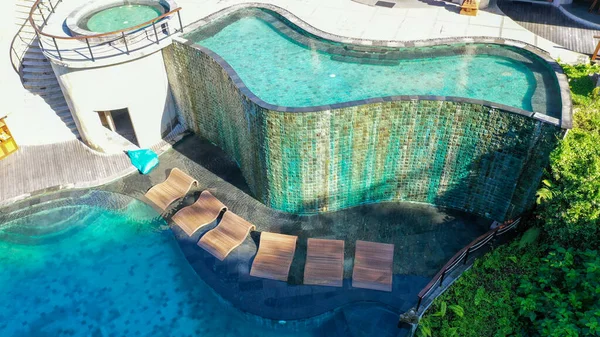 Бесконечный гостиничный бассейн в роскошном курорте. Вид сверху на роскошный круглый бассейн с белыми пумбреллами и шезлонгами в джунглях и пальмах. Шикарная вилла, бассейн в лесу, Убуд, Бали — стоковое фото