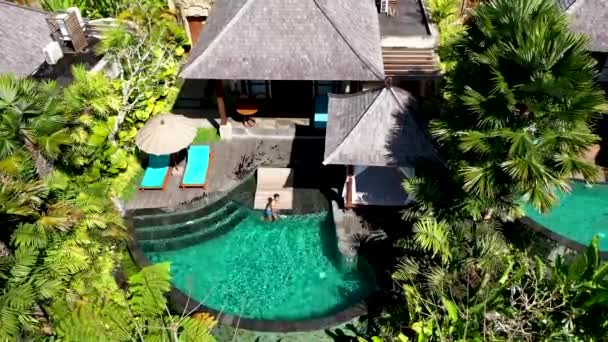 Jongeman zonnebaden bij het zwembad in luxe bungalow in tropische tuin. aziatische man looien genieten zomer dag — Stockvideo