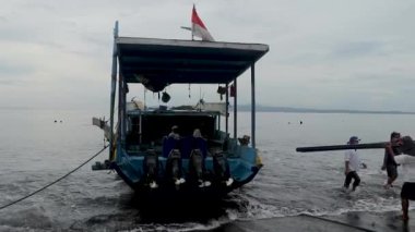 Sanur, Bali, Endonezya, 29 Mart 2021 İşçiler küçük Sanur limanındaki bir gemiye kargo yüklüyorlar. Erkekler bir tekneye plastik borular yükler.