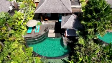 AERİAL. Lüks havuz manzarası ve üç genç adam ormanda havuzda eğleniyor ve dinleniyor.