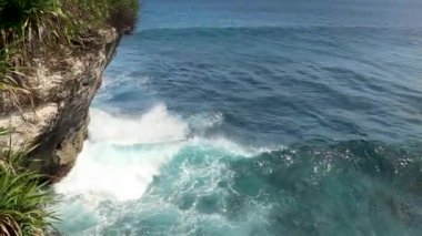 Büyük dalgalar yukarıdan geliyor. Mavi turkuaz okyanusta 4K drone görüntüsü, dalga kırma, badana. Deniz üzerinde güneşli bir gün. Büyük dalgalar sahil şeridini vurdu. Güçlü dalgalar Bali Endonezya