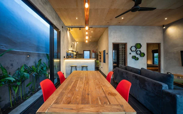 Amplio salón con suelo de madera y grandes ventanales, sofá de esquina gris y comedor de madera — Foto de Stock