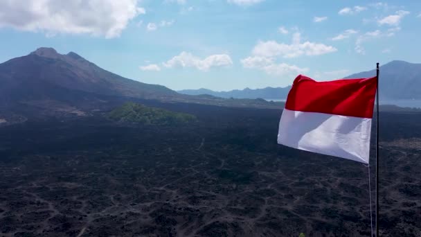 Indonéská vlajka vlaje ve větru u sopky Batur. Červená a bílá indonéská vlajka vlající ve větru izolované na modrém pozadí oblohy — Stock video