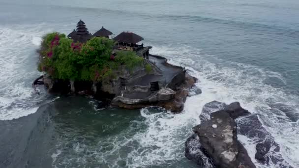 タナロット寺の息をのむような空中ビュー。タナロット(Tanah Lot)は、インドネシアのバリ島から形成された岩である。巡礼寺プラタナロットにその家。人気の観光文化アイコン — ストック動画