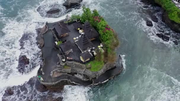 Overhead top down view of Tanah Lot temple surrounded by dangerous sea waves. Strong ocean waves crashing into small island with Hindu temple in Bali, Indonesia — Stock Video