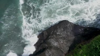 Uçan dronun üst hava manzarası turkuaz su, büyük köpüren dalgalar ve siyah kayalarla inanılmaz deniz manzarasını yakınlaştırıyor. Kara kum plajı, Bali Endonezya