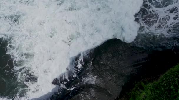 Vista aérea superior desde el avión no tripulado que vuela acercándose al increíble paisaje marino con grandes olas espumosas de agua turquesa y rocas negras. Playa de arena negra, Bali Indonesia — Vídeos de Stock