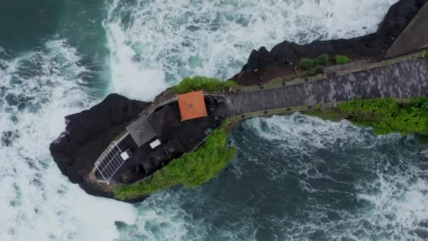Top down drone imagens do templo Batu Bolong com o donut e ondas batendo sobre as rochas — Vídeo de Stock