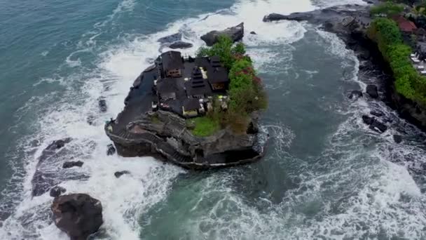 Pemandangan udara yang berputar di atas kepala dari bangunan-bangunan menakjubkan di kuil Tanah Lot di tebing laut yang gelap di laut yang kasar di Bali, Indonesia — Stok Video