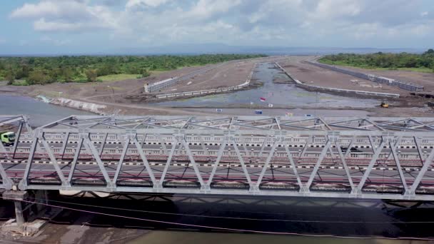 Konstruksi jembatan besi melawan langit biru dengan awan putih. Mengendarai di bawah jembatan, melihat jembatan dari bawah. Siluet salib balok baja. Detail jembatan terhadap langit biru cerah — Stok Video