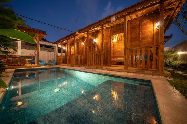 Casas tradicionales javanesas o casa de joglo. Villas de madera en estilo tradicional indonesio. Lugar de vacaciones perfecto con piscina. Concepto nocturno —  Fotos de Stock