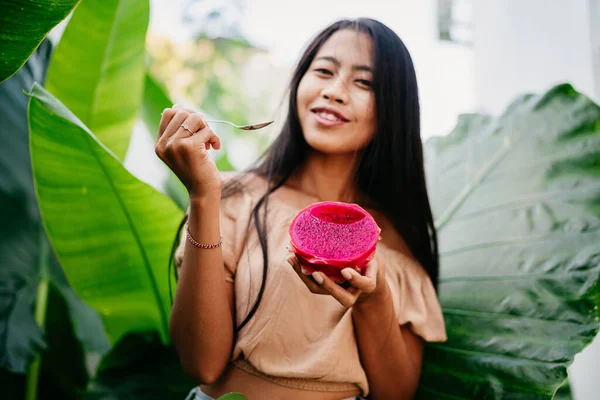 Jovem menina asiática em um segurando uma fatia de fruta de dragão tropical suculento brilhante. foco suave — Fotografia de Stock