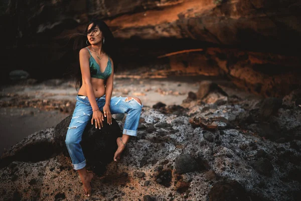 Jovem mulher asiática vestindo roupas sexy sentado na rocha durante o dia ensolarado de verão. Fundo rochoso — Fotografia de Stock