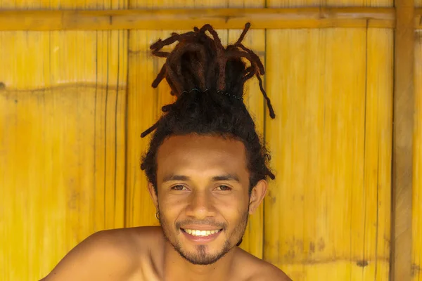 Retrato de sorrir cara local homem com dreadlocks com madeira no fundo — Fotografia de Stock