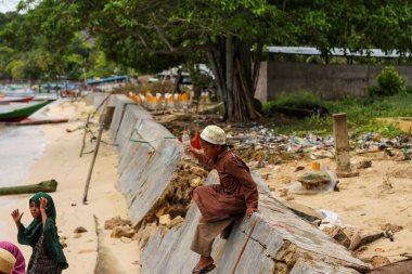 Labuan Bajo, Flores, Endonezya, 5 Nisan 2021. Doğu Nusa Tenggara sahilinde plastik şişeyle oynayan bir çocuk..