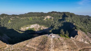 Close up of Kelimutu viewing platform perched on a volcanic ridge, surrounded by lush forest and overlooking the mysterious dark crater lake.