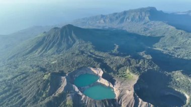 Kelimutu krater gölleri gerçek üstü renklerle parlar, volkanların dinamik ruhuna dair ipuçları veren gölgelerin ve orman tepelerinin arasında geçer..