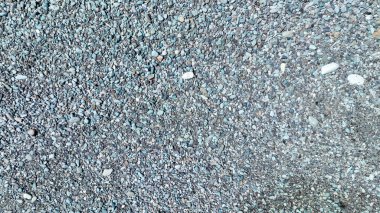 The beach transforms into a sea of rounded, pastel pebbles, each stone glistening under sunlight and shaping a colorful tapestry unique to Indonesias Batu Biru coastline.