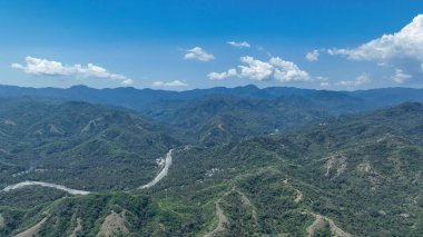 Orman ve tarlalardan oluşan bir yama üzerinde dik tepeler yükselirken, gümüş nehirler canlı tepelerde kıvrılarak merkez Flores 'in doğal dramasını vurguluyor..