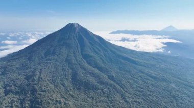 Yoğun tropikal ağaçlar, görkemli bir volkanın alçak yamaçlarını örtüyor. Ebu Lobo, kusursuz mavi gökyüzünün altında canlı büyümeyi ve dramatik ölçeği vurguluyor..