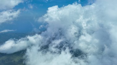 Inerie Dağı 'nın üzerinde süzülen drone, Flores' in en yüksek volkanının görkemli piramit zirvesini örten kabarık bulutları yakalıyor. Aşağıdaki sislerin arasından yemyeşil yamaçlar yükseliyor ve 2247 metrelik dramatik çizgisini vurguluyor..