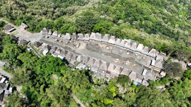 Bereketli zümrüt tepeler tarafından çerçevelenen Bena köyü, Flores dağlık arazilerindeki Ngada kültürünü koruyan geleneksel sazdan çatılı çatıları gibi tepe boyunca uzanır..