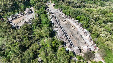 Kampung Bena 'ya insansız hava aracı görüntüsü yayarak, yoğun tropikal orman ihtişamıyla çevrili U şeklindeki atalarından kalma evleri gözler önüne seriyor..
