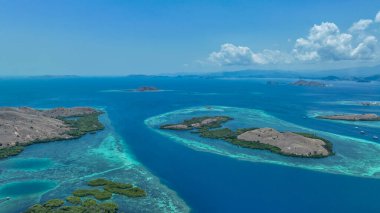 Mangrove püsküllü adalar zümrüt mücevher gibi uçar. Geniş bir mercan halkasının içinde. Komodo 'nun el değmemiş deniz tapınağı sergilenir..
