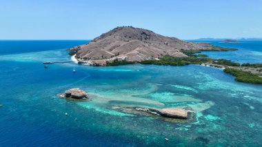 Yedi Mantar Komodo 'nun etrafındaki turkuaz sığlıkları kapatın. Kum yığınları mercanları kayaların üzerine bağlar, botlar canlı maviler içinde sürüklenir. Ejderhalar alemindeki büyüleyici resif bahçesi..