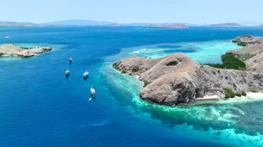 Komodo Ulusal Parkı filosu engebeli adaların ve turkuaz resiflerin yanından süzülüyor. Yatlar zümrüt kıyıları boyunca parlak bir yol izler, uzak tepeler mavi sise bürünür. Ejderha cennetine yelken açmak.