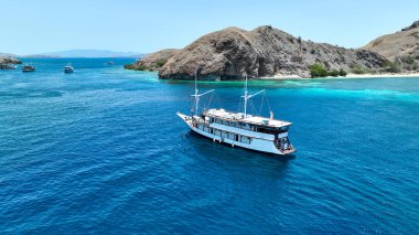 Engebeli tepeler ve sığ mercan çıkıntılarıyla çevrili Komodo sakin mavi kanalında zarif bir canlı süzülüyor..