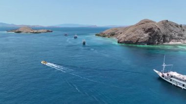 Parlak sarı bir ihale Komodo Ulusal Parkı kristal suları boyunca kayarak kayalıkların altında beyaz bir iz bırakıyor..