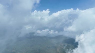 Pofuduk bulutlar Wolobobo 'nun yemyeşil tepelerinde dalgalanır. Mavi gökyüzü ve sisli ufuklarda Flores' in yemyeşil vadilerini ortaya çıkarır..