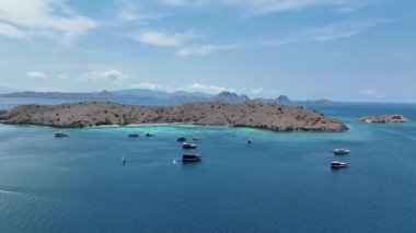 Komodo 'nun çorak tepelerinin eteklerindeki parlayan turkuaz resifler üzerinde kayıklar sürükleniyor. Orada el değmemiş mercan bahçeleri derin mavi kanallar ve sonsuz ada ufkuyla kesişiyor..