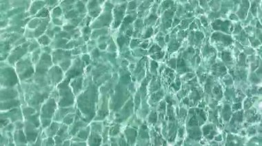 Işık yansımalı ve kum desenli kristal gibi sığ deniz suyu. Dokular, rahatlama, yaz temaları, doğa kavramları ve su geçmişi için idealdir..